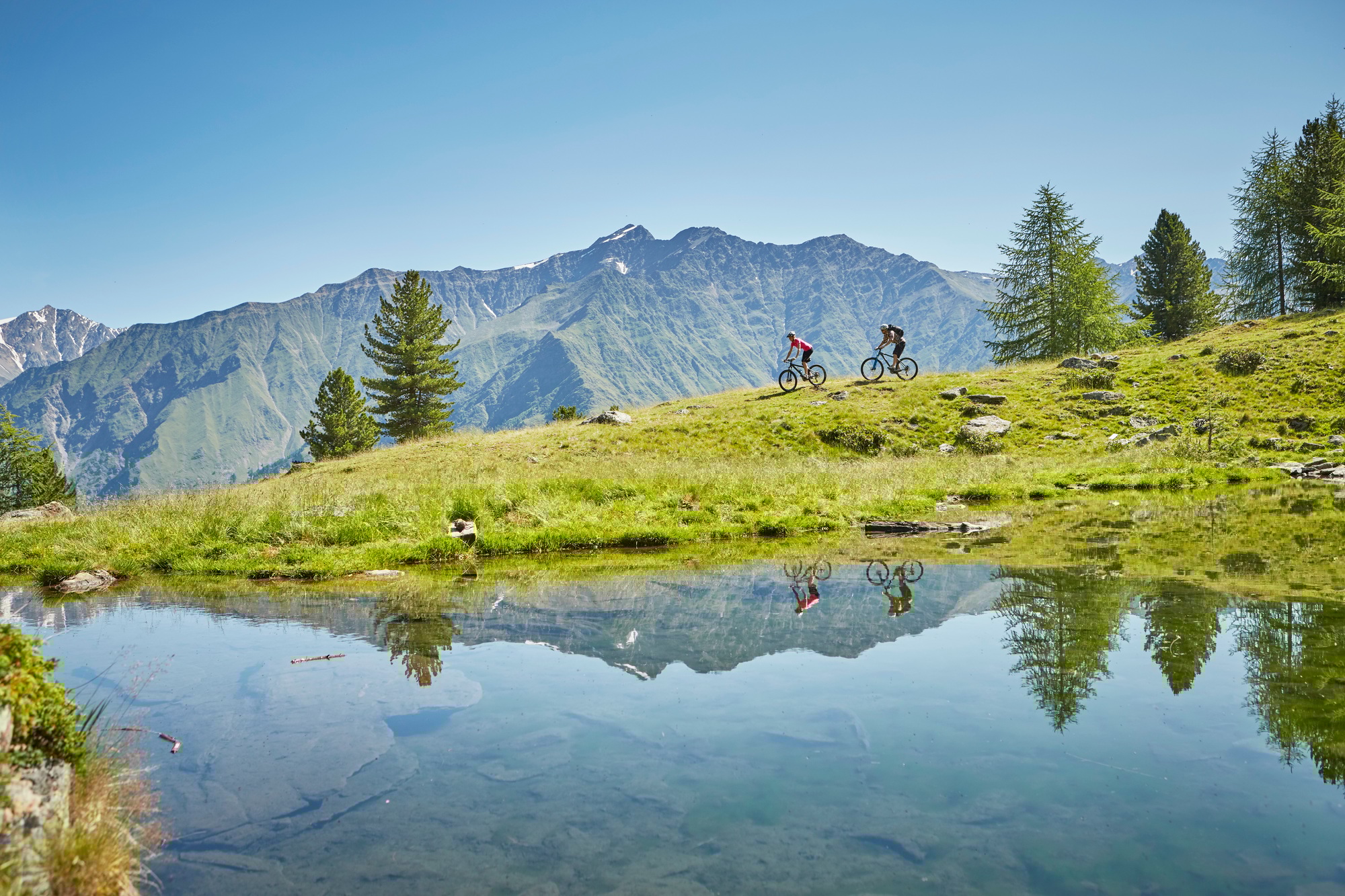 Young couple mountainbiking down hill, Karthaus, Val Senales, South Tyrol, Italy